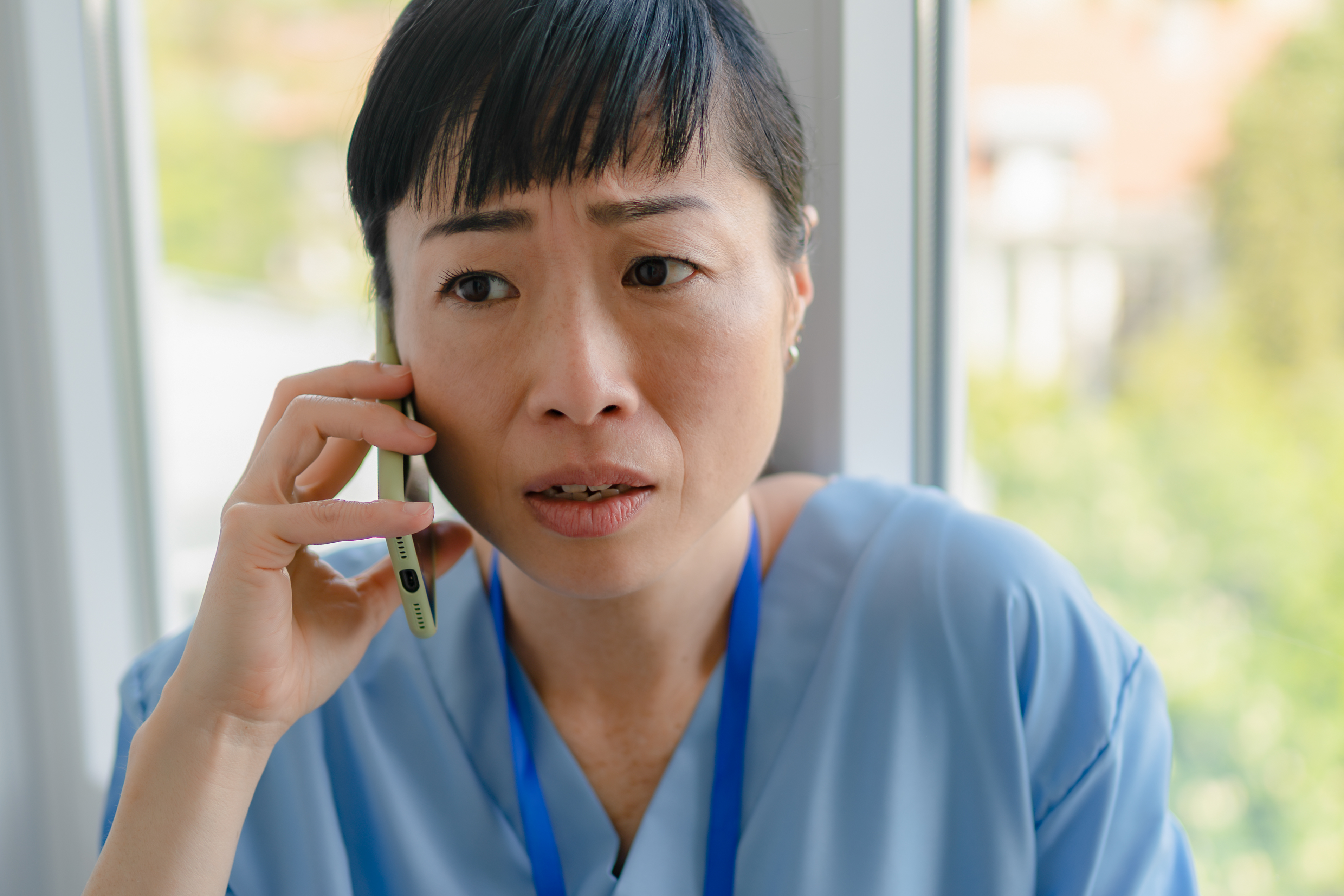 不安な表情で電話する女性